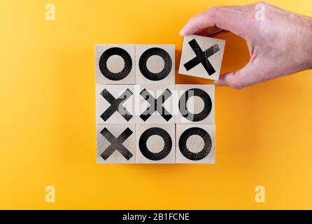 Draufsicht über Tic-tac-Toe-Spiel auf Holzspielzeugblöcken vor orangefarbenem Hintergrund, Sieg- und Scoring-Konzept Stockfoto
