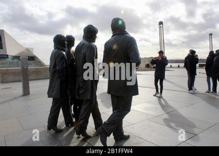 Touristen posieren mit einer Bronzestatue der beatles neben dem mersey in liverpool england UK Stockfoto