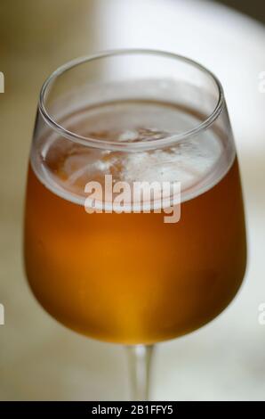 BRAUHAUS: Eine Nahaufnahme eines kalten Glases Bier mit Kondenswasser, das an der Seite tropft und kohlensäurehaltige Blasen mit einem schaumigen Deckel aufsteigen. Stockfoto