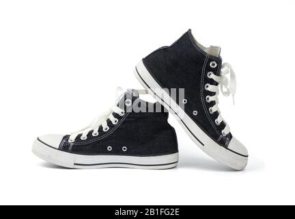 Paar schwarze Turnschuhe aus Textil mit weißen Schnürsenkeln, isoliert auf weißem Grund, Schuhe sind seitlich Stockfoto
