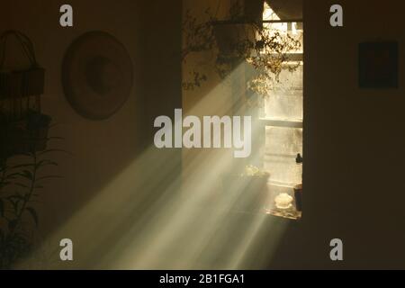 Lichtstrahlen aus einem Fenster in einem alten Landhaus. Himmlisches Licht in einem duschigen alten Haus. Stockfoto