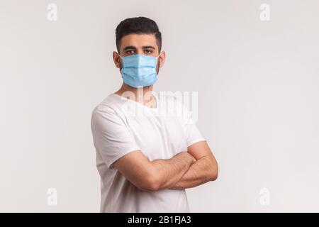 Effektiver Schutz gegen Coronavirus. Mann, der die Hände gekreuzt hält und eine hygienische Maske trägt, um Infektionen, Atemwegserkrankungen wie Grippe zu verhindern, 2 Stockfoto