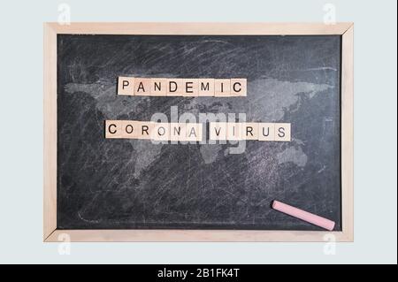 Pandemie-Corona-Virus Wort Holzklotz. Auf schwarzem Brett mit Weltkarte für Ihren Entstich, Draufsicht. Stockfoto