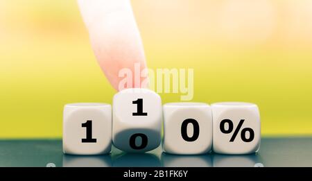 Hand dreht Würfel und ändert den Ausdruck "100%" in "110%". Stockfoto
