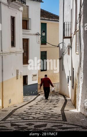 Ein Mann geht eine ruhige Straße in Alhama de Granada, Spanien hinunter Stockfoto