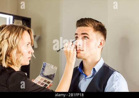 Hinteres Foto der Visagiste bei der Arbeit, die Modell-Makeup macht. Stockfoto