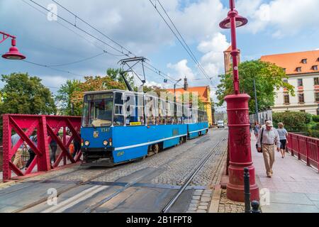 Wroclaw, Polen - 16. August 2019: Straßenbahn mit öffentlichen Verkehrsmitteln, die Touristen über die Sandbrücke (Most Piaskowy) zum historischen Zentrum transportiert Stockfoto