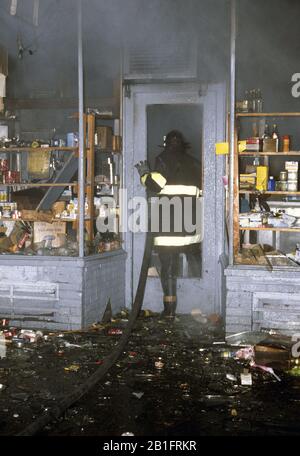 New York City Feuerwehrmann, der sich mit Brandanschlag im South Bronx Shop in New York City befasst Stockfoto