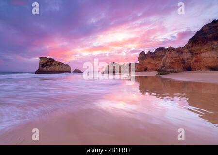 Ein farbenfroher Sonnenuntergang spiegelt sich an den feuchten Ufern von Praia Dos Tres Irmaos wider. Alvor, Portimao, Algarve, Portugal, Europa. Stockfoto