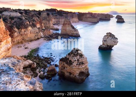 Ein farbenfroher Sonnenaufgang am Strand von Praia da Marinha, Caramujeira, Lagoa, Algarve, Portugal, Europa. Stockfoto