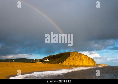 West Bay, Dorset, Großbritannien. Februar 2020. Wetter in Großbritannien. Ein Regenbogenbogen über East Cliff an der West Bay in Dorset während eines kurzen Sonnenbruchs, während eine Duschwolke über dem Kopf vorbeizieht. Bildnachweis: Graham Hunt/Alamy Live News Stockfoto