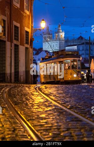 Die Straßenbahn Nr. 28 führt am Abend mit dem Kloster São Vicente de Fora auf die Straßen des Stadtteils Alfama. Lissabon, Portugal, Europa. Stockfoto