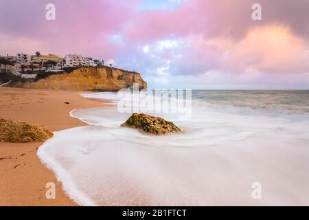 Am Strand von Praia de Carvoeiro erdrückende Wellen bei Sonnenuntergang. Carvoeiro, Lagoa Gemeinde, Algarve, Portugal, Europa. Stockfoto
