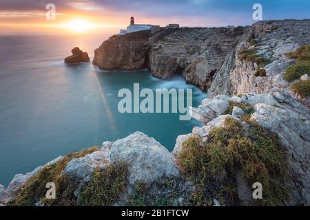 Die Klippen und der Leuchtturm von Cabo De San Vicente bei Sonnenuntergang mit Blick auf den Atlantik. Sagres, Vila do Bispo, Algarve, Portugal, Europa. Stockfoto