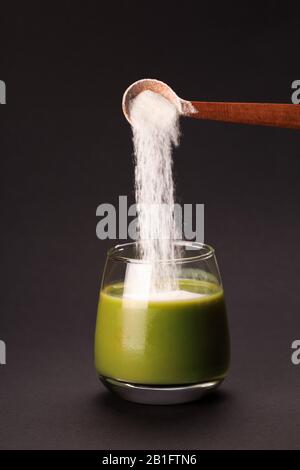 Grüner Saft mit Löffel von Protein oder Kollagen. Nahrungsergänzungsmittel Konzept Stockfoto