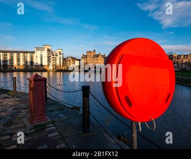 Leith, Edinburgh, Schottland, Großbritannien. Februar 2020. Wetter in Großbritannien: Sonnenschein in der Dämmerung beleuchtet alte und moderne Gebäude am Ufer, die sich im Wasser von Leith widerspiegeln. Das Malmaison Hotel (ehemalige Seemannsmission) und ein moderner Wohnblock namens Queen's Quay mit einem roten Rettungsboje Stockfoto