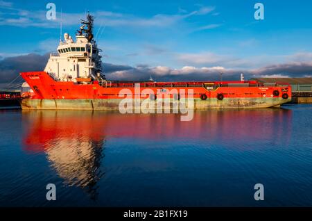 The Shore, Leith, Edinburgh, Schottland, Großbritannien. Februar 2020. Wetter in Großbritannien: Sonnenschein in der Dämmerung beleuchtet ein Schiff für die Versorgung vor der Küste, das sich im Wasser in Leith Docks widerspiegelt Stockfoto