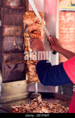 Ein Koch, der im fast Food Café kebabbes Fleisch mit Messer schneidet Stockfoto