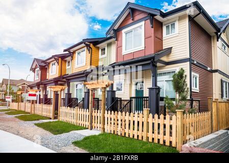 Nagelneue Reihenhäuser mit eingezäunten Vorgärten zum Verkauf in einer Wohnbebauung. Langley, BC, Kanada. Stockfoto