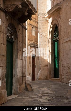 Eine schmale Passage hinter drei bunten Türen im historischen Zentrum von Ostuni, Apulien, Italien, Europa Stockfoto