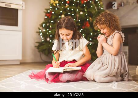 Zwei niedliche kleine Schwestern schreiben einen Brief an den Weihnachtsmann Stockfoto