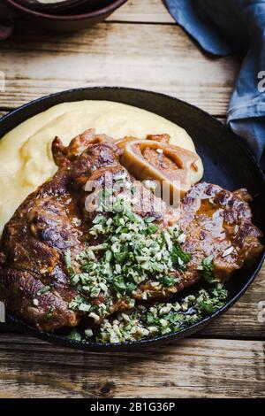 Osso Buco mit Gremolata, Gewürz aus Zerkleinerungs-, Knoblauch- und Zitronenschale, serviert mit Polenta. Traditionelle italienische Küche Stockfoto