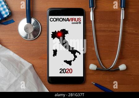 Coronavirus Konzept: Smartphone mit einer Karte von Italien mit einem roten Punkt auf der Region, in der die Ausbreitung der Infektion beginnt. Stethoskop und ein medizinisches Gerät Stockfoto