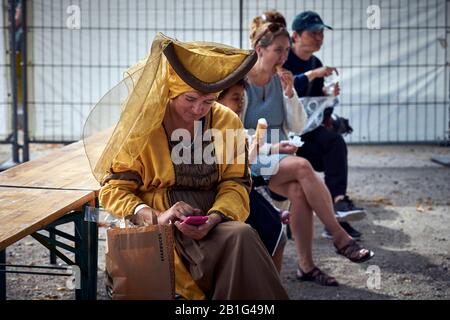 Eine Frau, die in mittelalterlichen Kostümen gekleidet ist, sieht ihr Telefon während einer Pause von der Veranstaltung an Stockfoto
