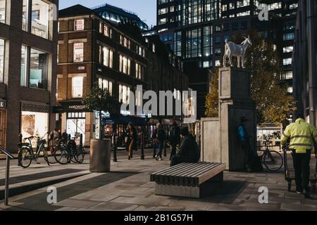 London, Großbritannien - 29. November 2019: I Goat Sculpture von Kenny Hunter in Spitalfields, London, Großbritannien, am Abend, Menschen, die spazieren gehen, Bewegungsunschärfe. Die Statistik Stockfoto