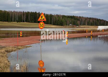 Überflutete Straße 11101 abseits des Highway 110. Die Straße wurde angehoben, um zu verhindern, dass sie von Hämjoki-Flusshochwasser abgeschnitten wird. Lohja, Finnland. Februar 2020. Stockfoto