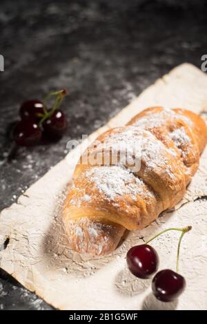 Erdbeere, Kirschroissant. Im rustikalen Stil, auf einem dunklen abstrakten Hintergrund. Stockfoto