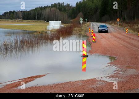 Überflutete Nebenstraße 11101 von Highway 110 in Südfinnland mit Verkehr. Der Fluss Hämjoki überschwemmt in Nummi-Pusula, Lohja, Finnland. Februar 2020. Stockfoto
