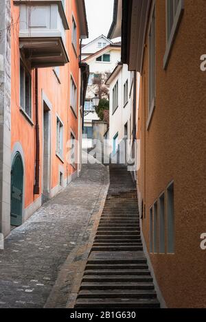 Züricher Gasse zwischen bunten Altbauten in der alten Innenstadt, Schweiz. Gasse in der Stadt Zürich. Eine Treppe auf einem Weg zwischen Gebäuden. Stockfoto