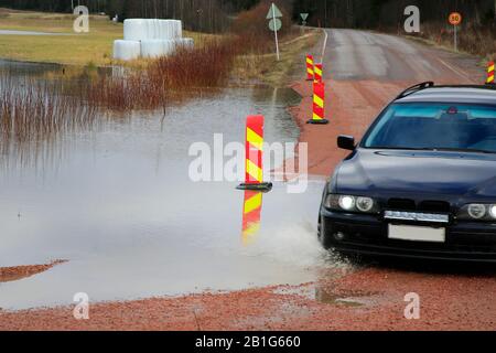 Auto auf überflutete Straße Nr. 11101. Die Straße wurde angehoben, um zu verhindern, dass sie von Hämjoki-Flusshochwasser abgeschnitten wird. Lohja, Finnland. Februar 2020. Stockfoto