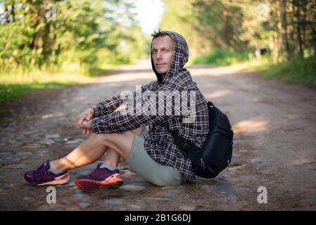 Der Mann sitzt auf der Straße und blickt in den Rahmen. Für jeden Zweck. Stockfoto