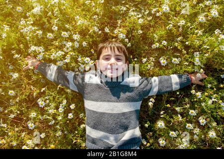 Kind lächelt im Frühling glücklich unter den Gänseblümchen Stockfoto