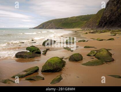 Farbfoto der Küstenfelsen am Strand einige geglättet und abgerundet durch die Passagen von Zeit und Flut mit Steinkobbeln und Kieselsteinen, die auf t liegen Stockfoto