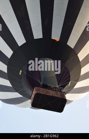 Schwarz-weißer Heißluftballon, der den blauen Himmel im Hintergrund abnimmt Stockfoto