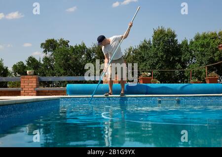 Reinigung des Schwimmbades. Man reinigt im Sommer den Außenpool mit Staubsauger. Saisonale Vorbereitungen. Reinigungssysteme für Stockfoto