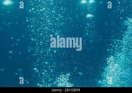 Blaue Meereswellen unter Wasser mit Blasen. Lichtstrahlen leuchten durch. Ideal für Hintergründe. Stockfoto