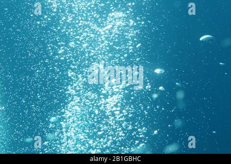 Blaue Meereswellen unter Wasser mit Blasen. Lichtstrahlen leuchten durch. Ideal für Hintergründe. Stockfoto