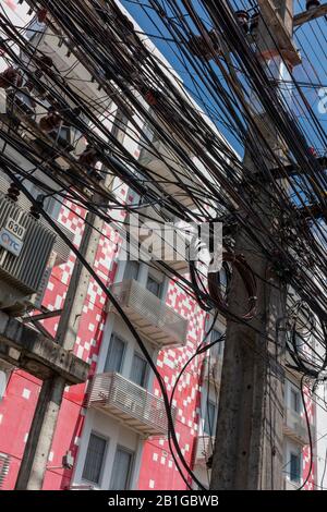 Ein Kabelgewirr von Telefonleitungen und elektrischen Kabeln auf einer Hauptstraße in patong, phuket, thailand. Stockfoto