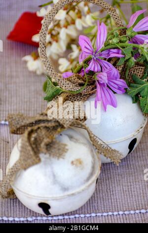 Zwei weiße Glocken zwischen einem osterroten Ei und Frühlingsblumen Stockfoto