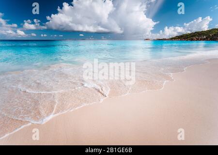 Weiße Wolken über der blauen Ozeanlagune mit ruhigen Wellen am tropischen Strand. Hintergrundbild zum Sommerurlaub Stockfoto