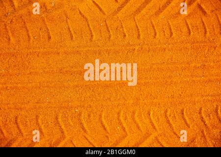 Orangefarbene Autoreifenbahn auf dem Sand. Strecke von einem Autoreifen auf dem Sandhintergrund. Stockfoto