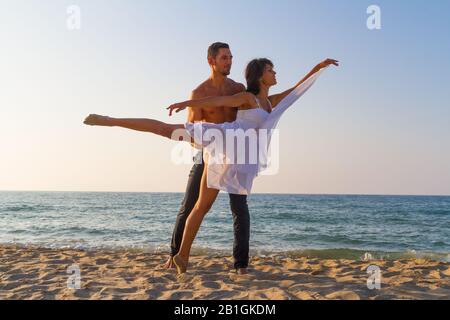 Sport fit Junges Paar am Strand Üben Acro Yoga Fitnessübungen und balancieren in Paar an einem Sommertag in der Dämmerung. Gesunder Lebensstil und Stockfoto