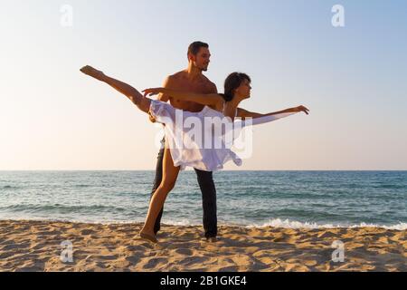 Sport fit Junges Paar am Strand Üben Acro Yoga Fitnessübungen und balancieren in Paar an einem Sommertag in der Dämmerung. Gesunder Lebensstil und Stockfoto