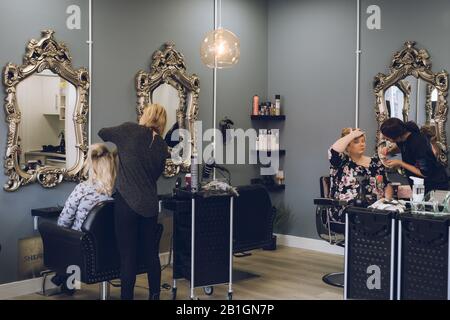 Das Innere eines Friseursalons mit einem Haarkleiderstyling und einem Makeup-Künstler, der Makeup aufgibt Stockfoto