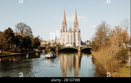 Strasbourg, Frankreich - 16. März 2014: Umbau der St. Paul's Church das bedeutende Gebäude der Gotik Revival-Architektur und eines der Wahrzeichen der Stadt Straßburg - Batorama Touristenboot auf Dem Fluss Ill Stockfoto