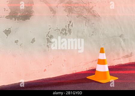 3D-Computergrafik, ein rot-weiß gestreifter Verkehrskonus gegen eine rötliche Wand Stockfoto